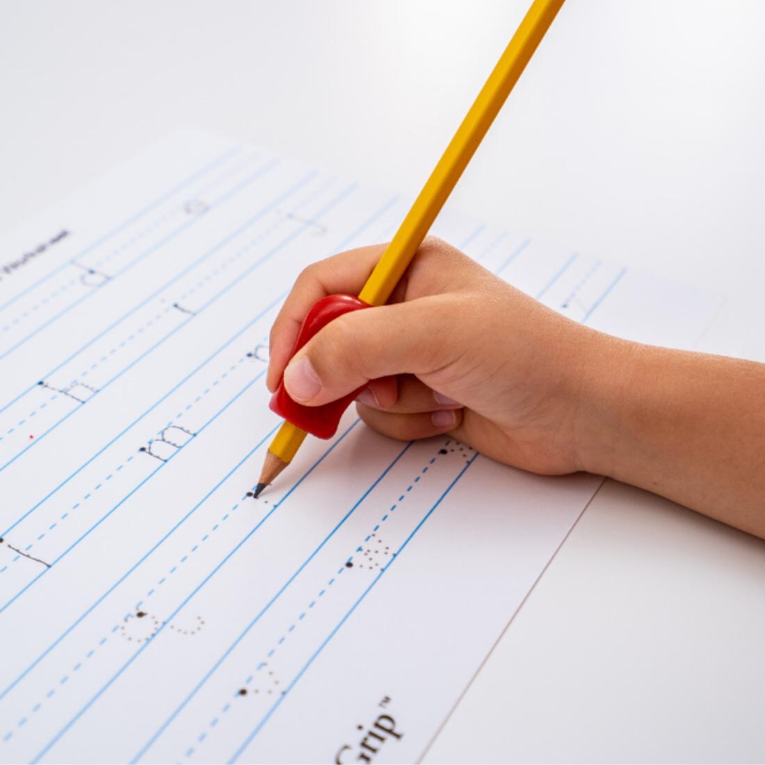 hand tracing letters on a page, using a pencil with The Pencil Grip Regular Size Bright grip