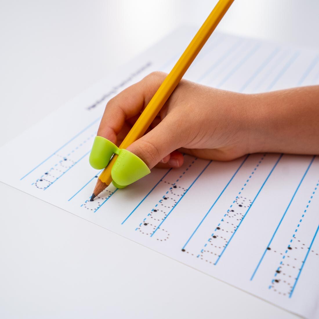 hand tracing letters on a page, using a pencil with The Claw Grip, size small
