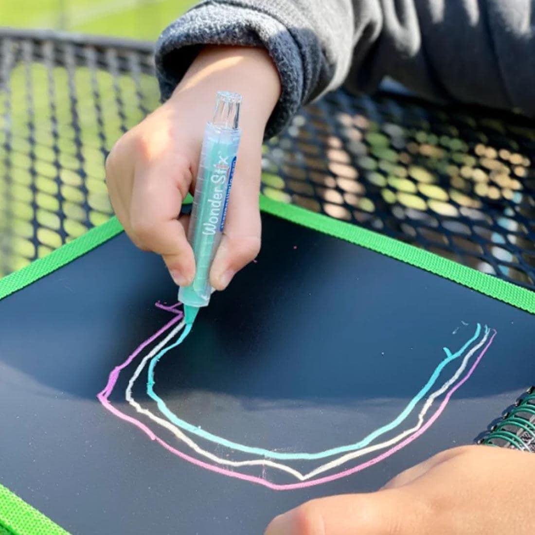 child's hands using a Wonder Stix to draw on the Sea Life Daily Doodler Reusable Activity Book