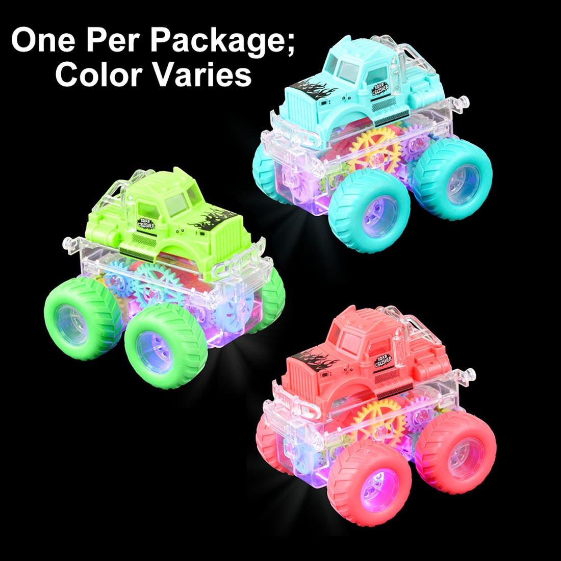 Three Friction Gear Light-Up Big Wheel Toy Trucks lit up in the dark with text One Per Package; Color Varies