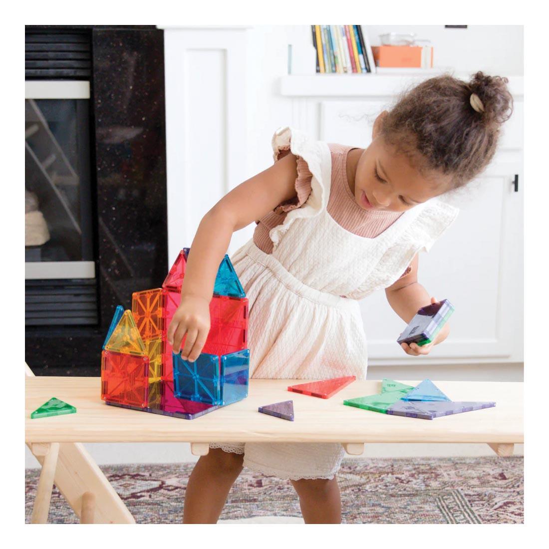 Young girl building with Magna-Tiles Clear Colors 100-Count Set