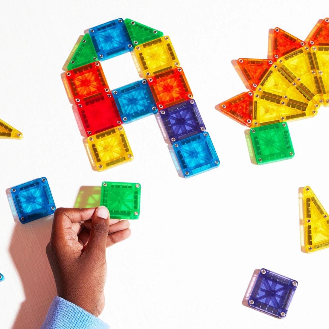 child's hand building with Magna-Tiles microMAGS Clear Colors