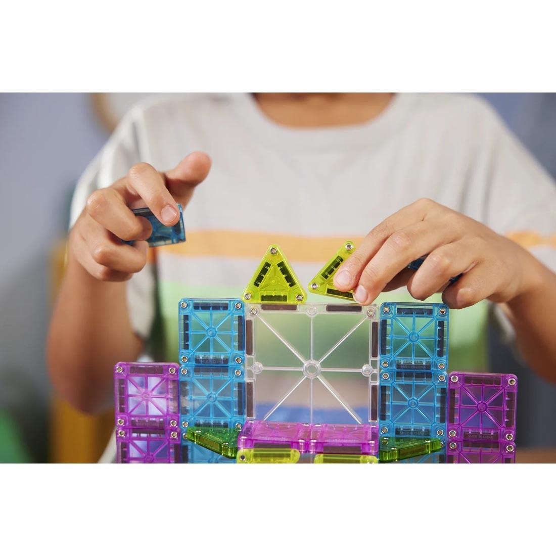 child building with Magna-Tiles microMAGS Travel Deluxe 55-Piece Set