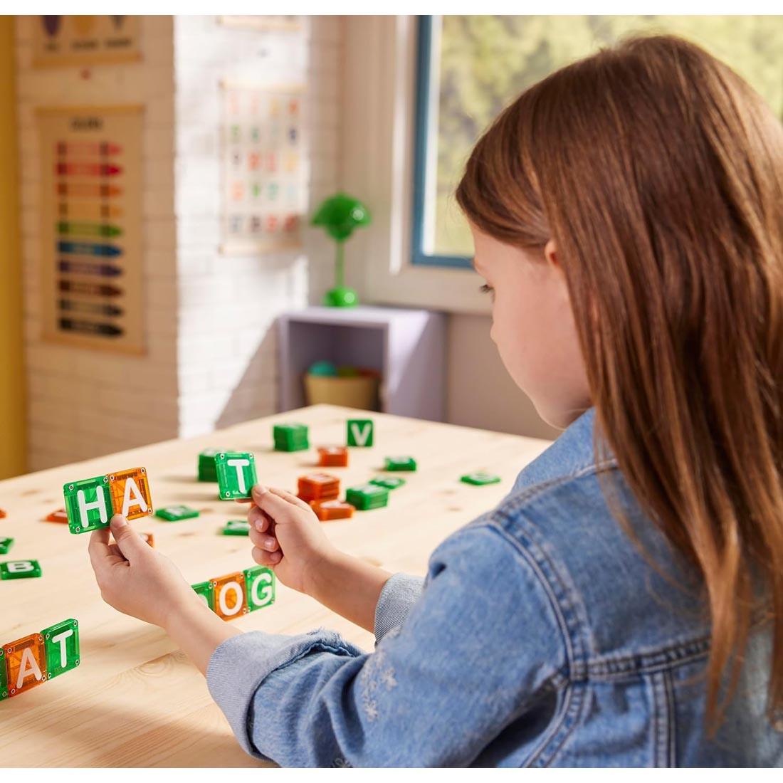 child using the Magna-Tiles microMAGS Learn Letters 56-Piece Set