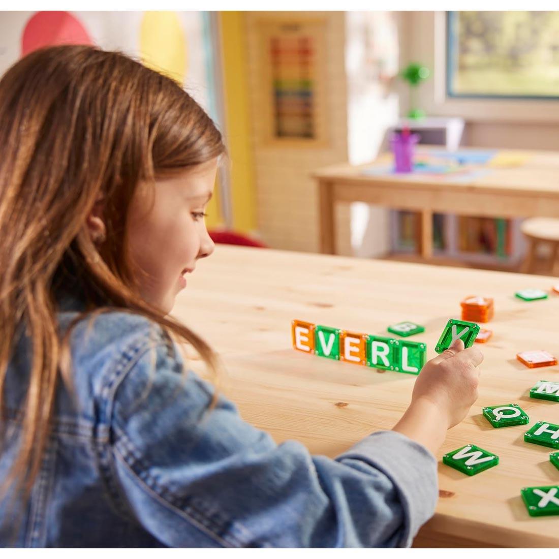 child using the Magna-Tiles microMAGS Learn Letters 56-Piece Set