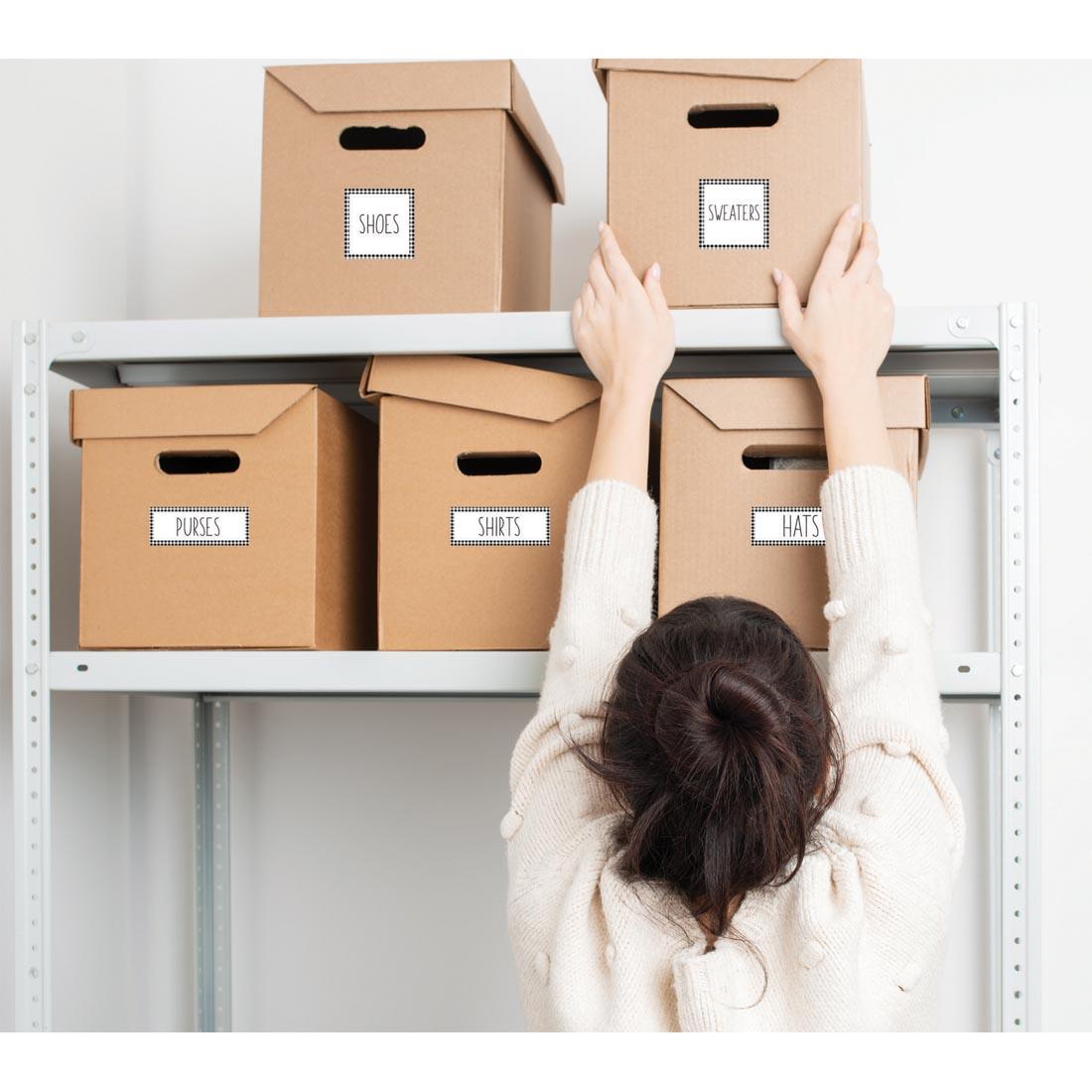 person reaching for a box labeled with Wallies Square & Rectangle Dry Erase Labels