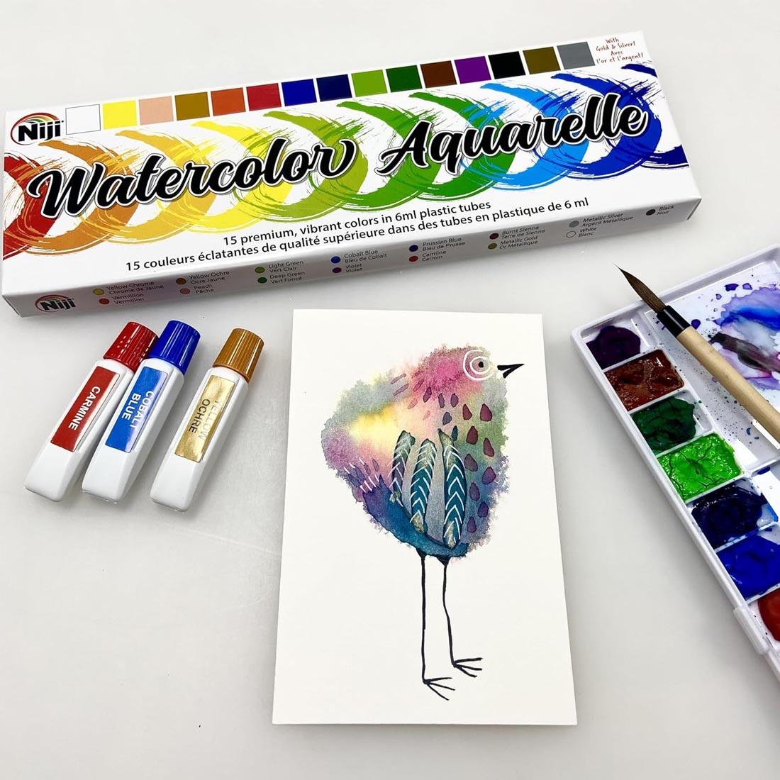 package of Niji Watercolor Aquarelle 15-Color Set above 3 paint tubes, a painting and a filled palette with brush